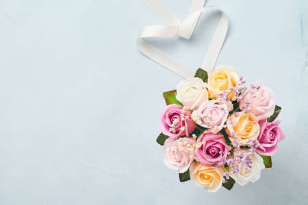 Festive composition with beautiful delicate roses flowers in pink round box on light blue background. Flat lay, copy space. Greeting card.の写真素材