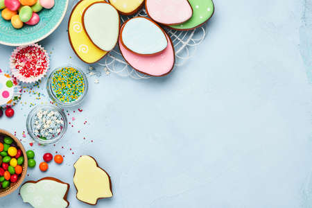 Easter baking background. Easter multicolored gingerbread, candy and confectionery topping dressing on blue background. Celebratory background concept. Space for text.の写真素材