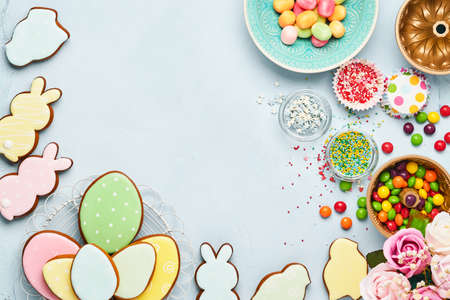 Easter baking background. Easter multicolored gingerbread, candy and confectionery topping dressing on blue background. Celebratory background concept. Space for text.の写真素材