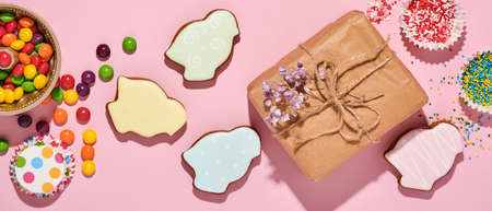 Easter baking background. Easter multicolored gingerbread, candy, scattered confectionery topping dressing and gift box on pink background. Celebratory background concept. Space for text.の写真素材