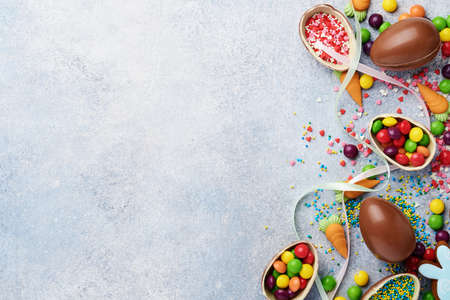 Chocolate easter eggs and colorful sweets on gtay background greeting card. Top view. Flat lay with...