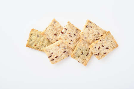 Stack of grain salty crackers with bran and flax seeds on white background. Top view.