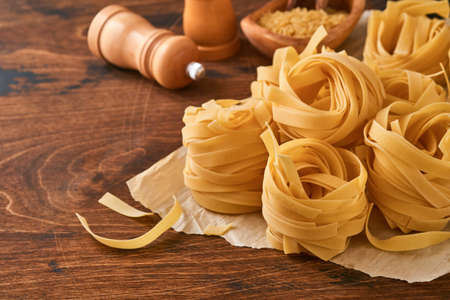 Homemade tagliatelle pasta in brown paper on an old wooden background.の写真素材