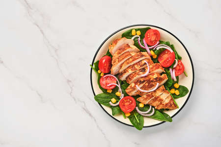 Chicken fillet with salad spinach, cherry tomatoes, cornflower and onion. Healthy food. Keto diet, diet lunch concept. Top view on white background.の写真素材