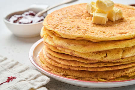 Crepes or thin pancakes stack with butter and raspberry jam on beautiful ceramic plate on an old...