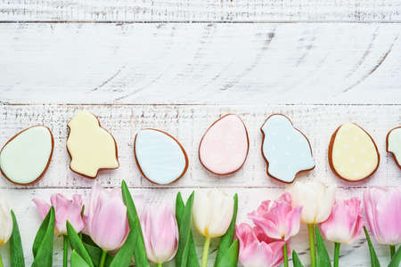 Easter table setting with floral decor and plate with easter gingerbread on white table. Elegance dinner. Mock up. Top view.の写真素材