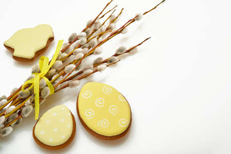 Easter. Pussy willows branches yellow ribbon and easter gingerbread hares, chickens and eggs isolated on a white background.の写真素材
