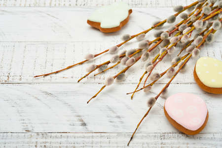 Easter. Pussy willows branches yellow ribbon and easter gingerbread hares, chickens and eggs on old wooden white background.の写真素材