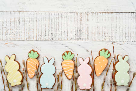 Pussy willows branches and Colorful easter gingerbread rabbit, eggs and chickens on white old wooden background. Festive Easter concept with copy space. Flat lay.の写真素材