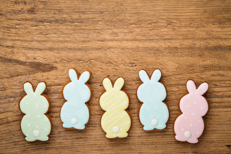 Easter composition with easter rabbits cookies gingerbread on wooden background. Festive concept or greeting card with copy space. Flat lay, top view.の写真素材