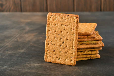 Cracker with flax seeds and oat bran rectangular shape for healthy, dietary and balanced diet on dark wooden background. Snack for proper nutrition.の写真素材