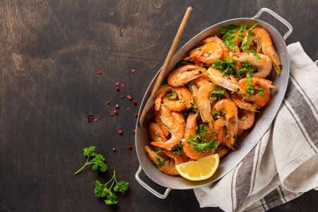 Roasted shrimps with garlic, lemon and parsley, black background, top view, copy spaceの写真素材