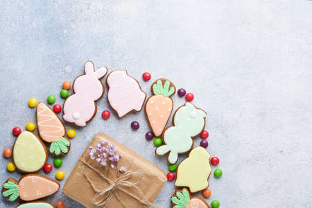 Easter eggs, cookie and colorful sweet made in shape of circle wreath on gray background. Minimal holiday concept with copy space for text. Flat lay pattern.の写真素材