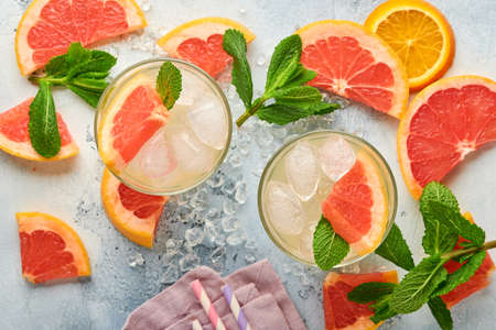 Lemonade drink made from grapefruit, soda water and mint leaves with ice on light blue slate, stone or concrete background. Healthy homemade lemonade or cocktail. Mock up. Top view.の写真素材