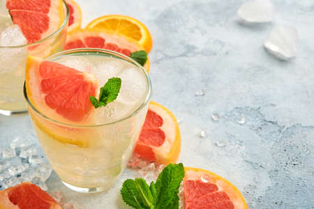 Lemonade drink made from grapefruit, soda water and mint leaves with ice on light blue slate, stone or concrete background. Healthy homemade lemonade or cocktail. Mock up. Top view.の写真素材