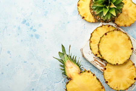 Sliced ripe pineapple on light blue stone background. Tropical fruits. Top view. Free space for...