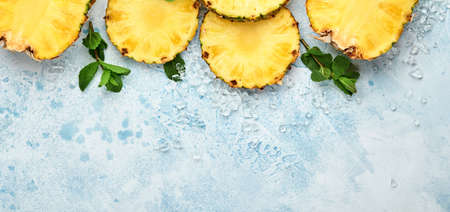 Sliced ripe pineapple on light blue stone background. Tropical fruits. Top view. Free space for text. Mock up.の写真素材