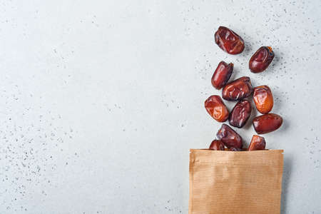 Dried sliced date fruit in paper bag on white background with copy space. Snack vegan sugarfree food.の写真素材