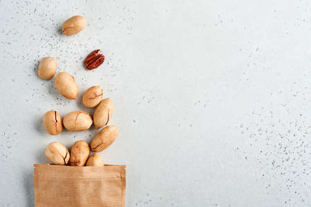 Nuts pecan in paper bag on white background with copy space. Snack vegan sugarfree food.