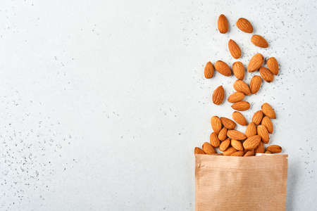 Almond nut in paper bag on white background with copy space. Snack vegan sugarfree food.