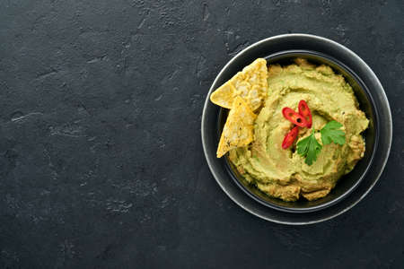 Guacamole. Traditional latinamerican Mexican dip sauce in a black bowl with avocado and ingredients...