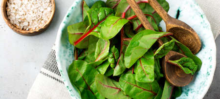 Fresh swiss chard leaves or mangold in ceramic dish on gray light concrete background. Concept for...