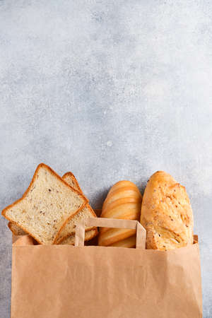 Mixed bread in a paper bag on light gray concrete stone table. Top view with copy spaceの写真素材