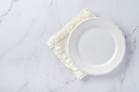 Empty white plate and towel over white marble table for your recipe or menu. Top view. Mock up.の写真素材