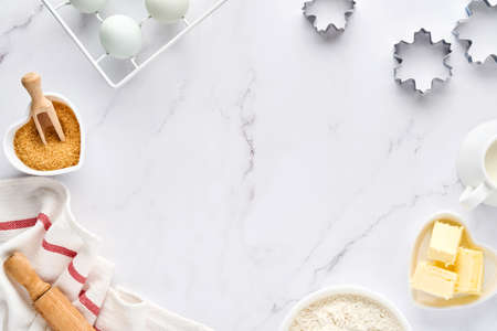 Baking background with flour, eggs, kitchen tools, utensils and cookie molds on white marble table. Top view. Flat lay style. Mock up.の写真素材