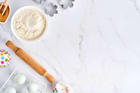 Baking background with flour, eggs, kitchen tools, utensils and cookie molds on white marble table. Top view. Flat lay style. Mock up.の写真素材