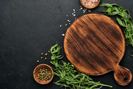 Fresh tarragon. Branch of fresh herb seasoning and cooking products, tomatoes, peppers, onions and olive oil on black concrete background. Cooking Background. Top view.の写真素材