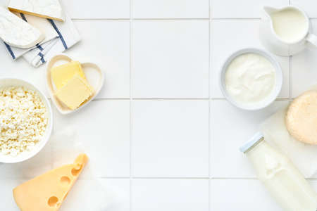 Glass of milk, cottage cheese, ricotta, sour cream, cheese, camembert and butter on white table background. Different dairy products. Milk concept. Top view with copy space. Mock up.の写真素材