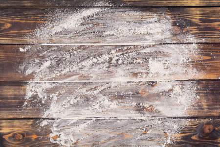 Flour scattered in the form of a circle, rolling pin and white linen napkin on an old wooden background. Place for text. Background for bakingの写真素材
