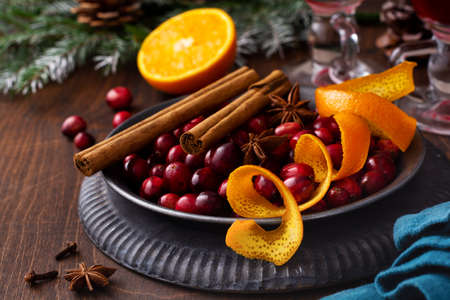 Ingredients for making mulled wine with cranberries. Orange, cinnamon, cranberry berries, cloves, anise and sugar. Christmas atmospheric retro concept. Place for textの写真素材