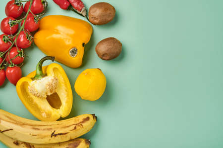 Assortment of fresh pepper, chili, bananas, cherry tomato, lemon and kiwi in craft paper bag over...