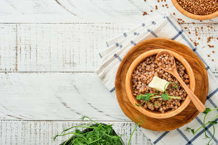 Buckwheat porridge in bowl with parsley leaf and butter on old white wooden background. Homemade food. Gluten free ancient grain for healthy diet. Top view. Copy space.の写真素材