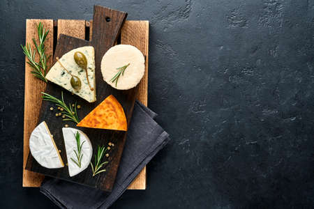 Set or assortment cheeses. Suluguni with spice, camembert, blue cheese, ricotta, maasdam, brie cheese. Top view. On black background. Free copy space.の写真素材