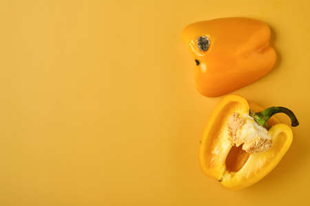 Moldy and wrinkled rotten yellow peppers. Concept of unhealthy, decompose, spoiled vegetables. Garbage dump rotten food on yellow background. Top view. Waste conceptの写真素材