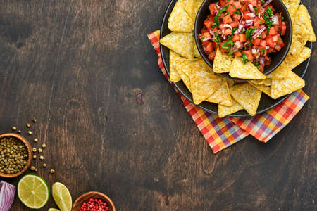 Traditional Mexican tomato sauce salsa with nachos and ingredients tomatoes, chile, garlic, onion on...