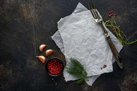 Black stone cooking background. Piece of old parchment paper, spices and vegetables. Top view. Free...
