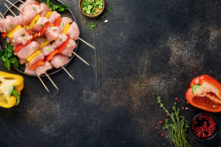 Raw shish kebab on wooden board, spices, herbs and vegetables on dark gray background. Barbecue Raw ingredients for goulash or shish kebab. Top view. Free copy space.の写真素材