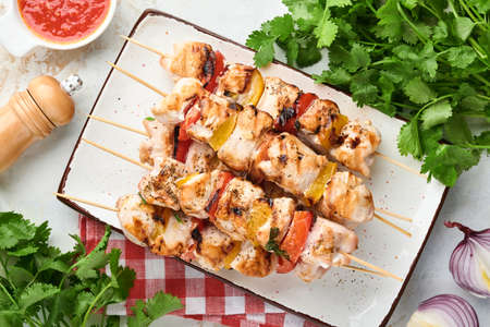 Chicken shish kebab or skewers kebab in ceramic plate, spices, cilantro herbs and vegetables on...