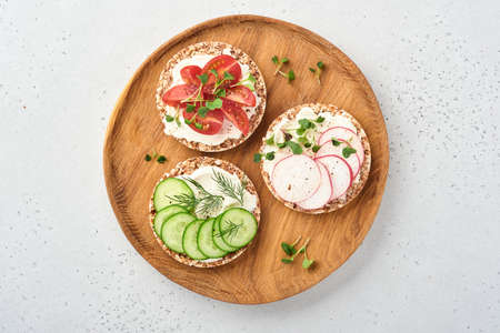 Three crispy buckwheat bread gluten free with cream cheese, radish, tomato, cucumber, and microgreen...