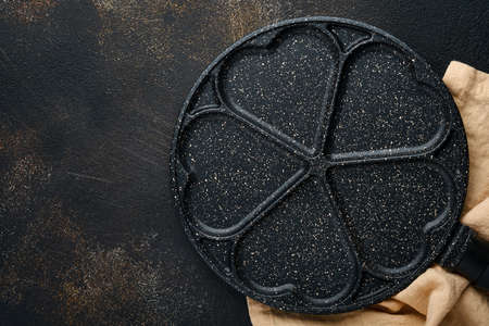 Empty frying pan black, skillet with stone nonstick coating for baking pancakes in shape of breakfast hearts and ingredients on gray concrete table background. Breakfast for Valentines Day. Top view.の写真素材