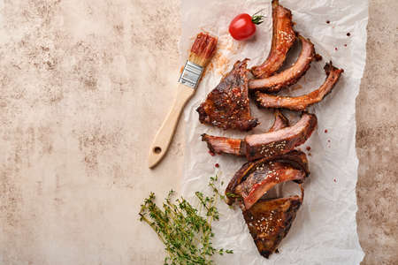 Grilled and smoked pork ribs with barbeque sauce on an old vintage wooden cutting board on old concrete table background. Tasty snack to beer. Top view.の写真素材