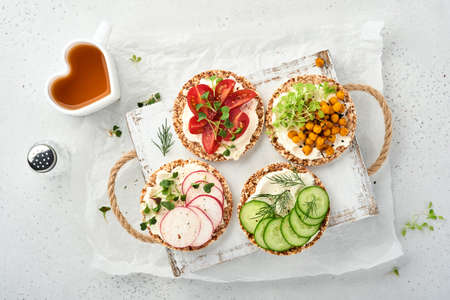 Four crispy buckwheat bread with cream cheese, radish, tomato, chickpea, cucumber and microgreen for...
