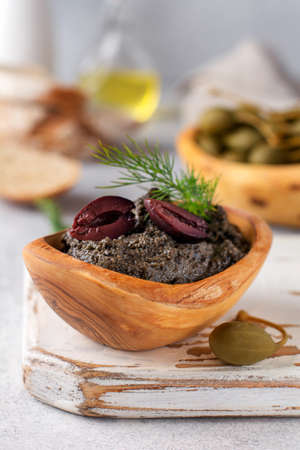 Black Tapenade or tapas, traditional Provence dish or dip with olives and basil on an old wooden table background. Selective focus. Top viewの写真素材