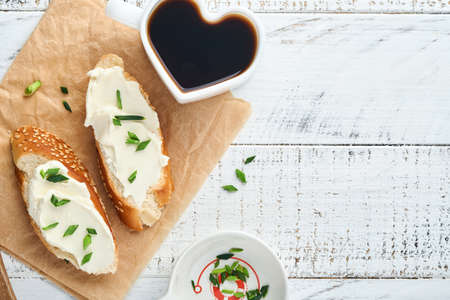 Sandwich with soft cheese with green onions and bread on old white wooden background. Simple breakfast with ricotta sandwich and coffee. Top view copy space for text.の写真素材