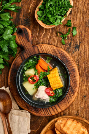 Chilean meat soup with pampkin, corn, fresh coriander and potatoes on old wooden table background. Cazuela. Latinamerican food.の写真素材