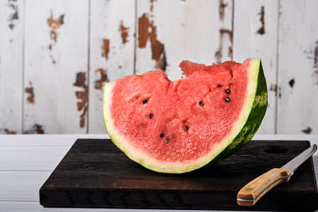 Female hands cut a watermelon into pieces against the backdrop of a home environment. Selective focus.の写真素材